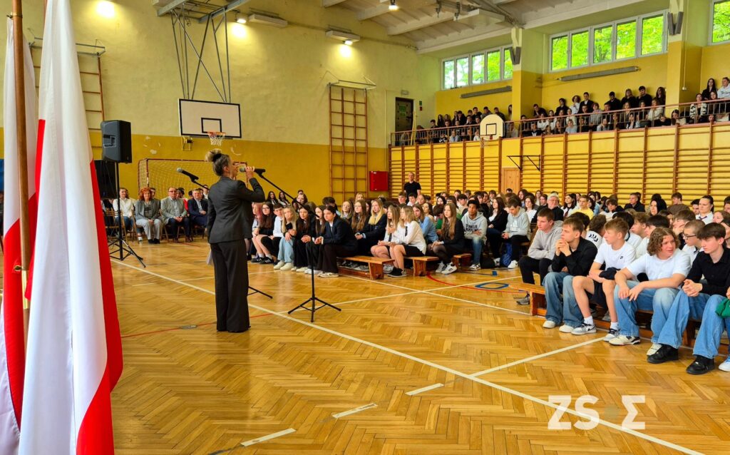 Nauczyciel zapowiadający wystąpienie. Uczniowie podczas apelu.