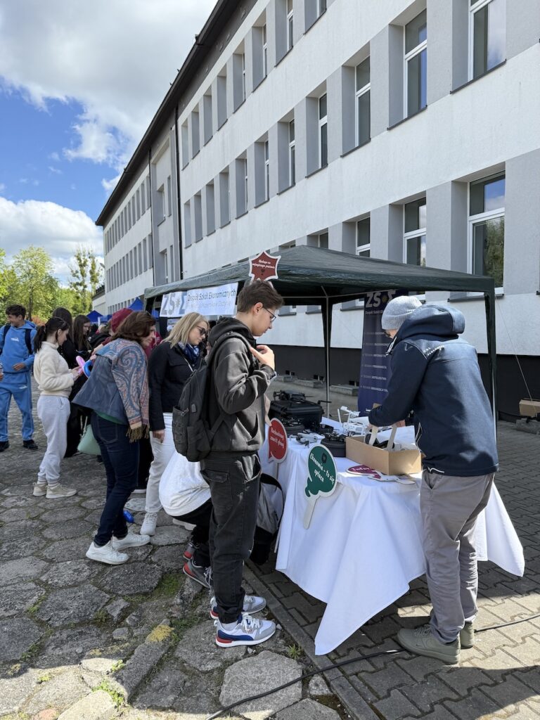 Nauczyciel wraz z uczniami przy stoisku podczas Zawodowej Majówki.