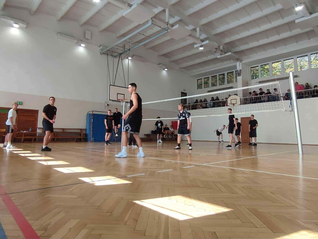Uczniowie na boisku, grający w siatkówkę.