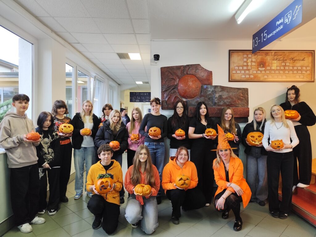 Uczniowie i nauczyciel pozują z dyniami