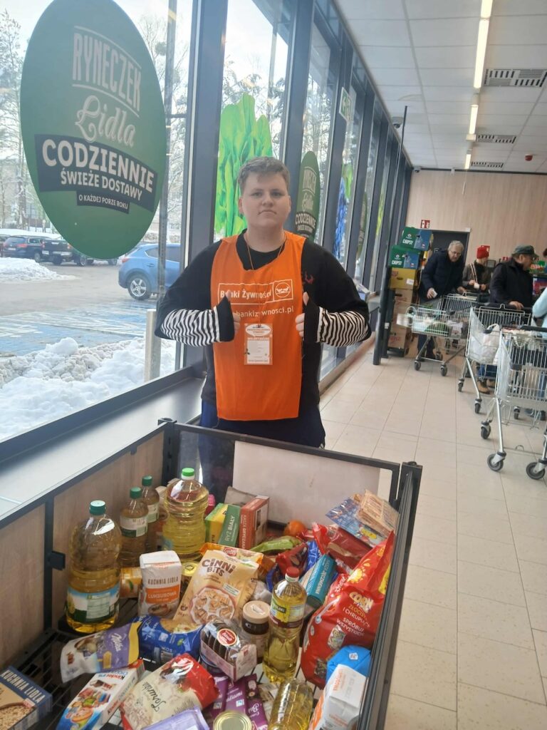 Uczeń i świąteczny kosz na zbiórkę żywności