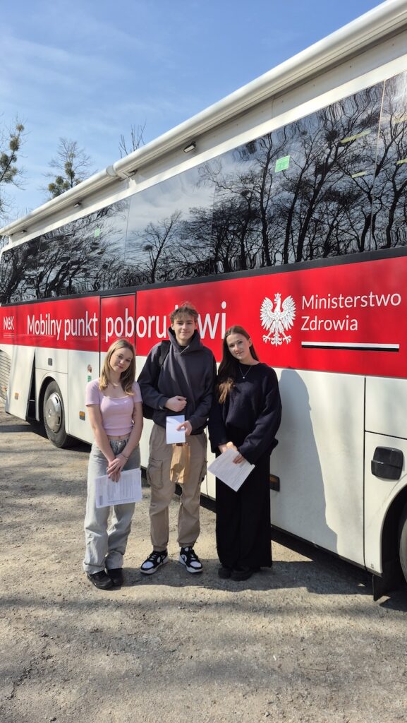 Grupa uczniów przed busem.