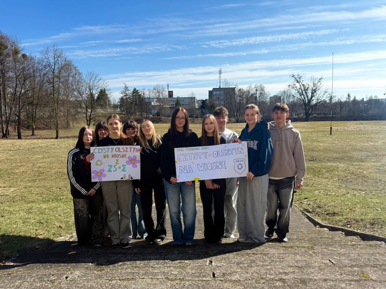 Uczniowie z plakatem na świeżym powietrzu.